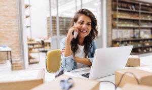 Woman working on laptop and phone at a small business